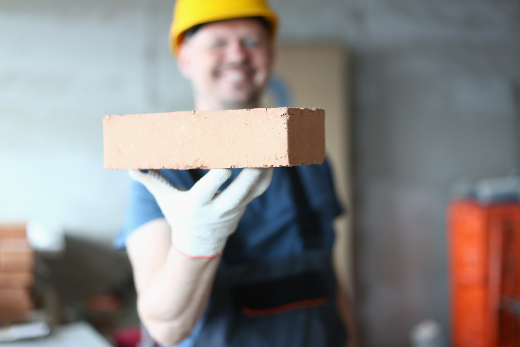 Master Builder Man Holding Red Brick at Construction Site